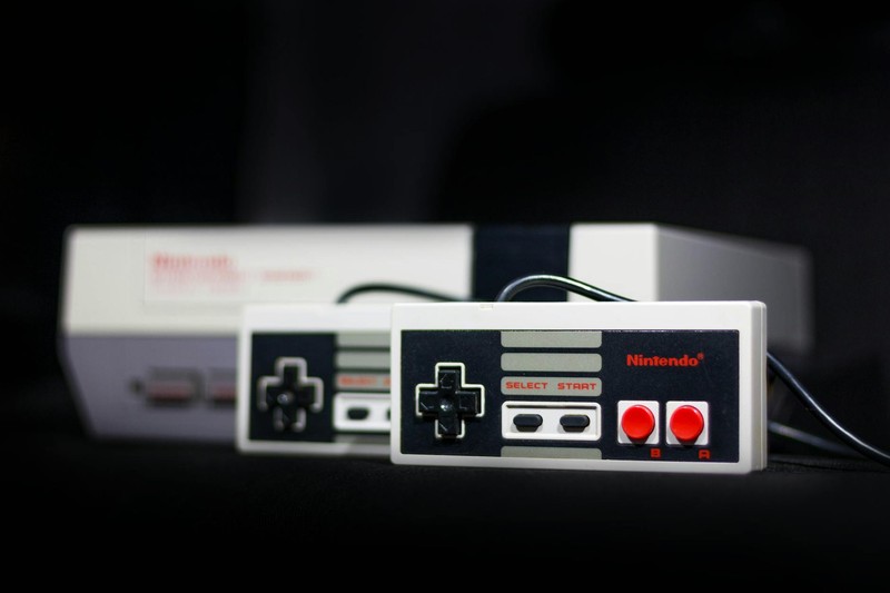 A classic Nintendo NES controller and console in close-up on a dark background