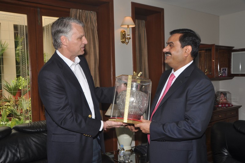 Gautam Adani in a formal meeting exchanging a ceremonial memento with a visiting diplomat at Adani House in Ahmedabad