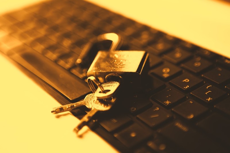A brass padlock with keys resting on a computer keyboard, symbolizing digital encryption and security