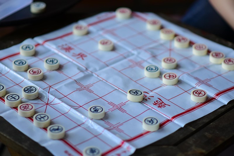 Close-up of a Chinese chess (Xiangqi) game in progress on a traditional board with pieces arranged in mid-game