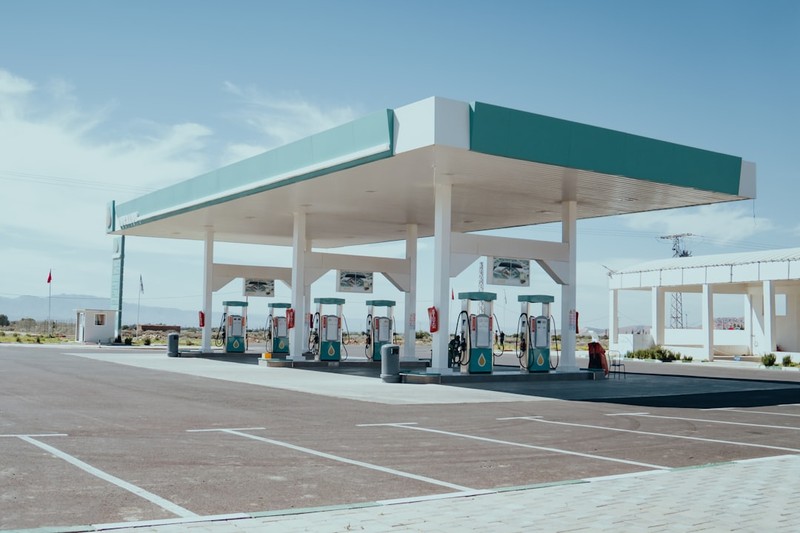 A gas station with fuel pumps under a green and white canopy on a clear day