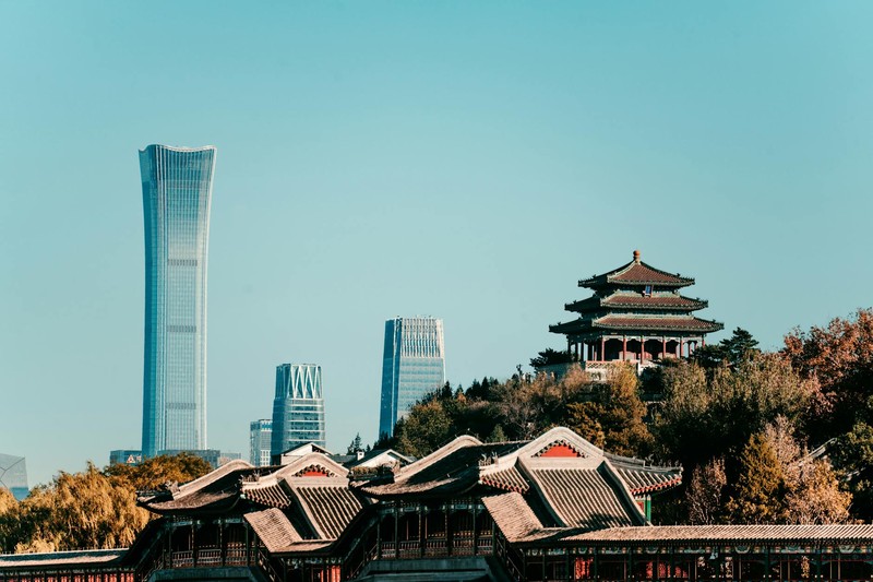 Beijing skyline featuring traditional Chinese architecture and the China Zun skyscraper under a clear blue sky