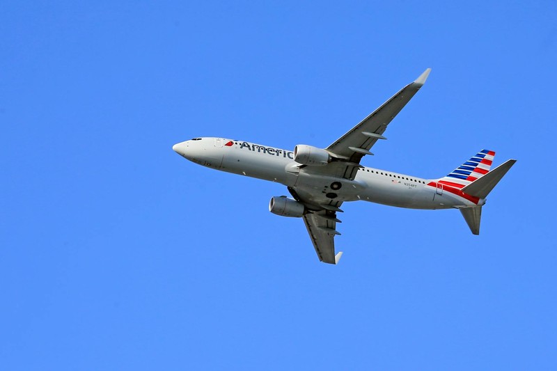 A Boeing 737 aircraft flying under a clear blue sky
