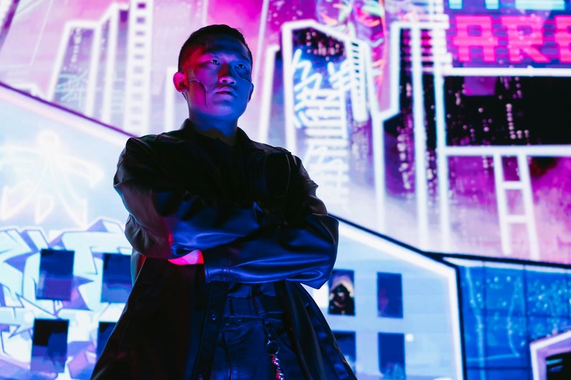 A person stands in a neon-lit cyberpunk cityscape at night with vibrant pink and blue lights