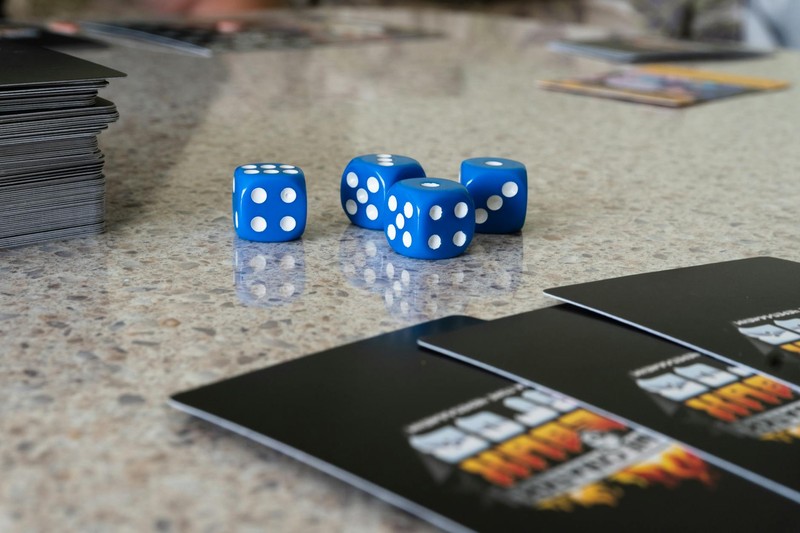 Blue dice and black game cards arranged on a speckled countertop surface