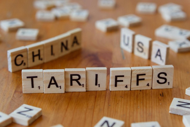 Scrabble tiles spelling CHINA, TARIFFS, and USA on a wooden table