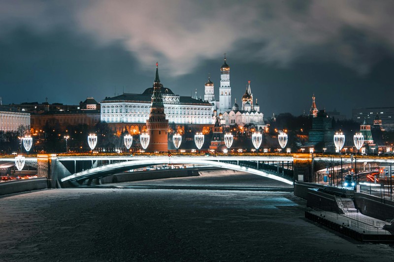 The Moscow Kremlin illuminated at night with the Moskva River and bridge in the foreground