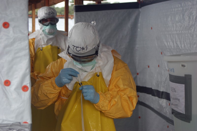 Healthcare workers in yellow protective PPE suits inside an Ebola treatment unit