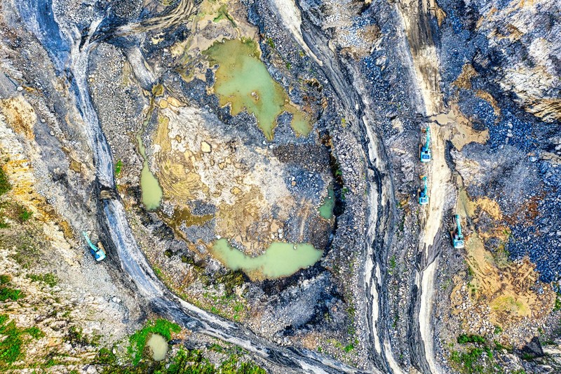 Aerial view of a large-scale mining excavation site with heavy machinery and exposed earth