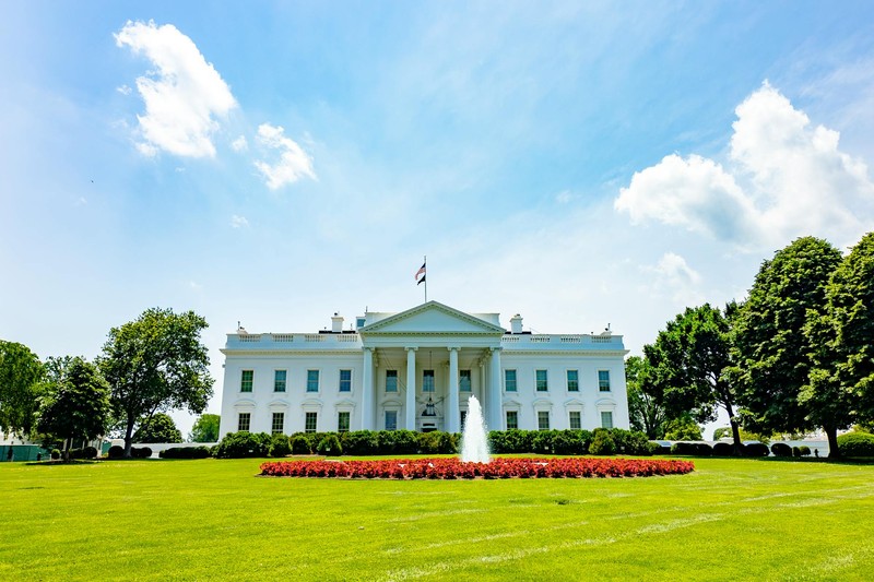 The White House on a bright summer day with the South Lawn fountain and American flag