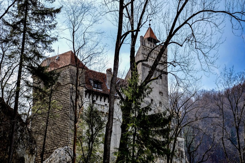 Bran Castle, known as Dracula's Castle, perched on a rocky hilltop surrounded by forested mountains in Romania