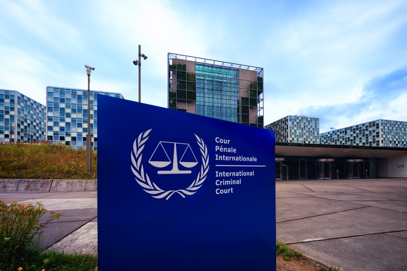 The International Criminal Court building in The Hague, Netherlands, with its prominent blue entrance sign visible.