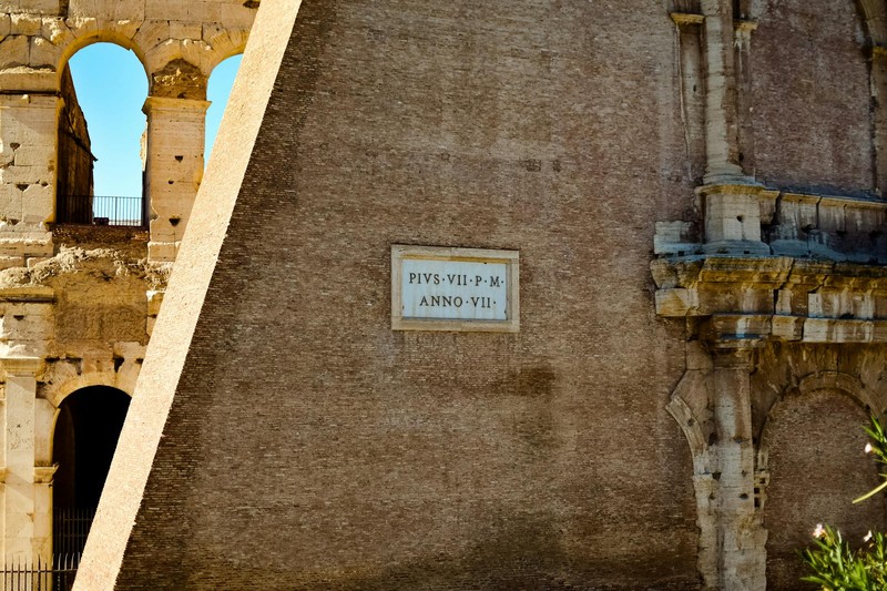 Detailed view of the ancient Colosseum walls in Rome with arched openings and weathered stonework under blue skies