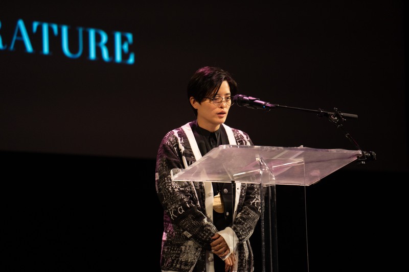 Yáng Shuāng-zǐ speaking at a podium during the 2024 National Book Awards finalist reading