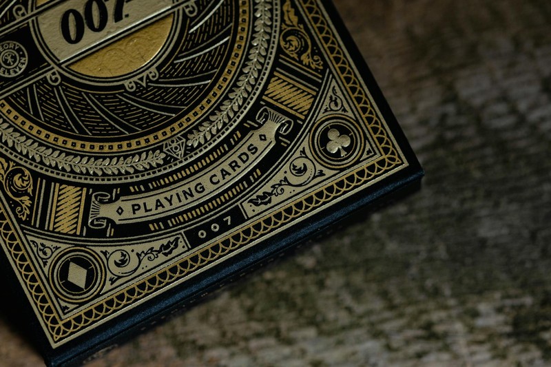 Close-up of a luxury 007 James Bond themed playing card box with gold ornate design on a dark background