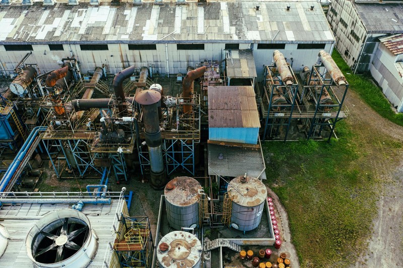 Aerial drone view of an oil refinery with storage tanks, cooling towers, and pipelines