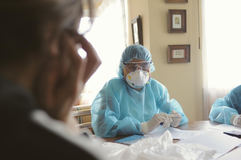 Healthcare worker in full PPE conducting a consultation during a health crisis