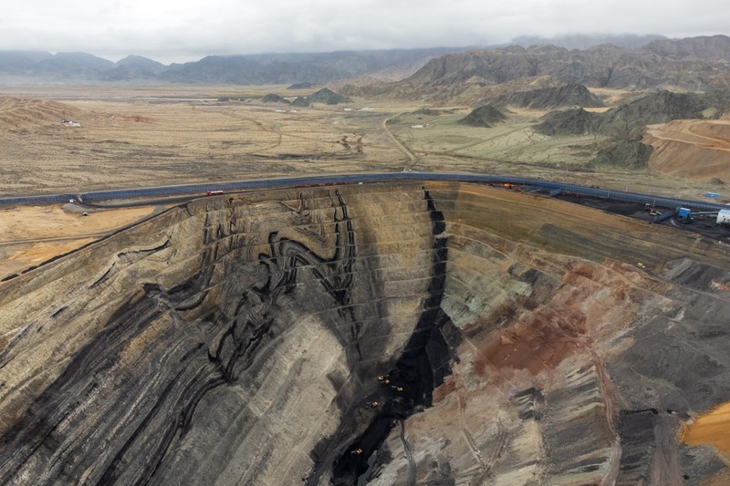 Aerial view of a large open-pit coal mine in China with exposed rock layers and mining roads