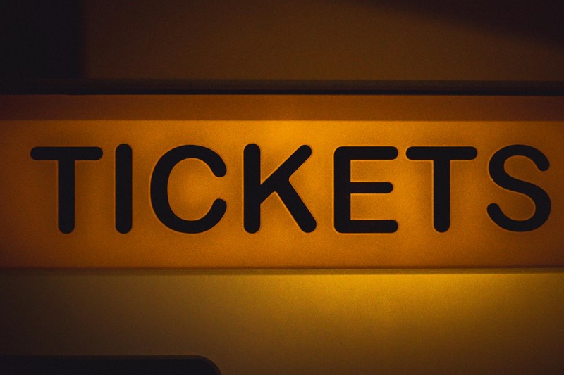 Illuminated yellow 'TICKETS' sign against a dark background