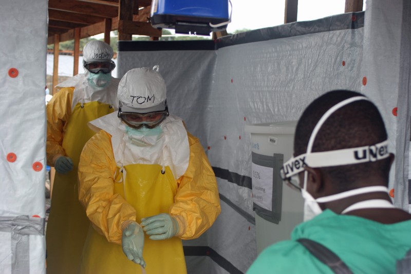 Health workers in yellow protective suits inside a temporary Ebola treatment unit with plastic sheeting walls