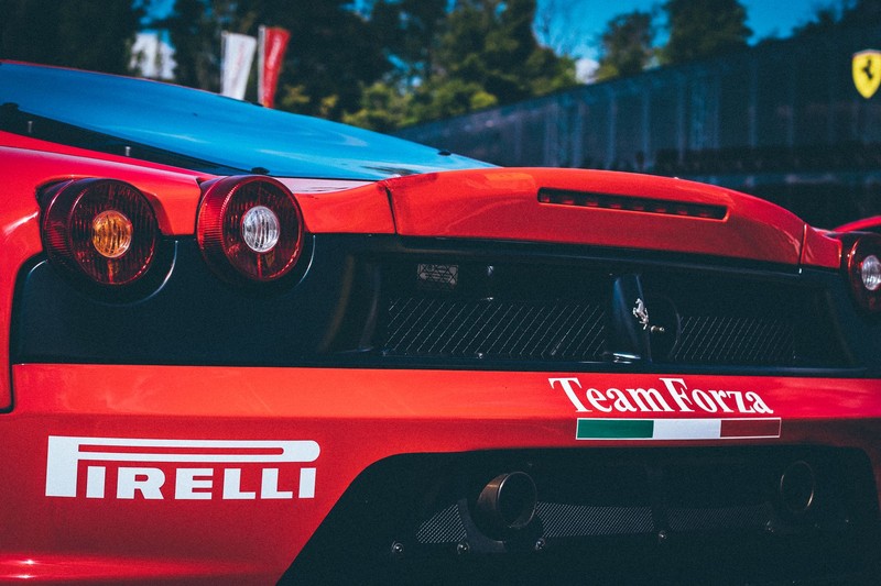 Red Ferrari sports car with Team Forza and Pirelli branding at an outdoor racing event