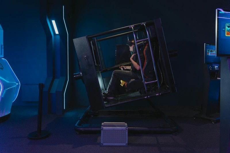 A person using a motion simulator in a high-tech gaming environment with blue neon lighting