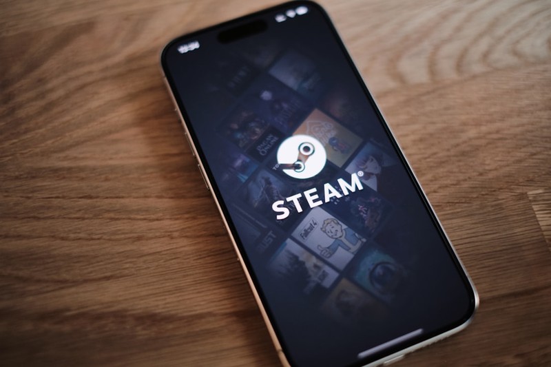 A smartphone displaying the Steam app on a wooden table