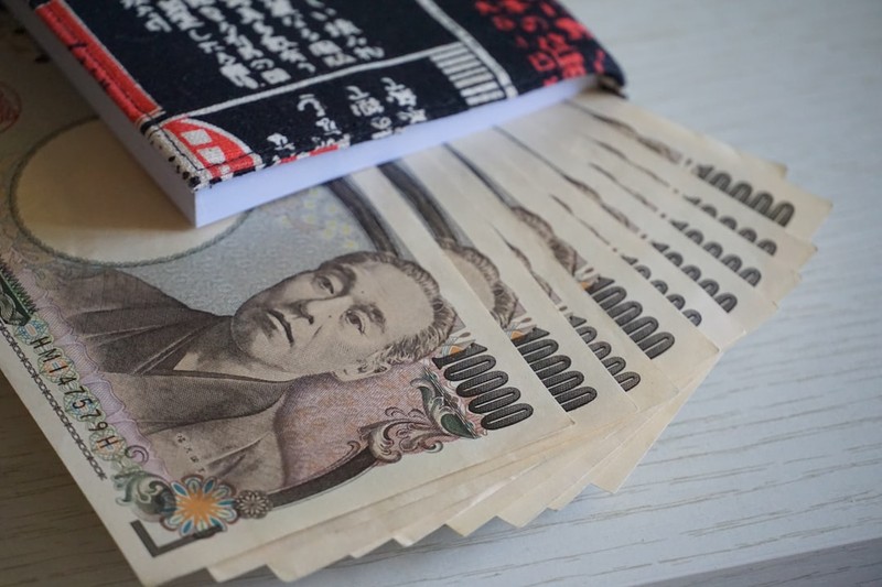 Fanned Japanese 10,000-yen banknotes featuring Fukuzawa Yukichi on a light surface