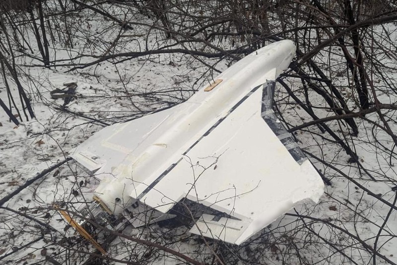 A white Russian Gerbera drone lying intact on snow-covered ground surrounded by bare winter branches