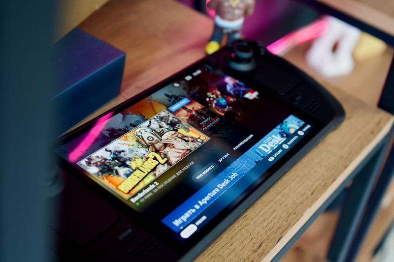 A Steam Deck OLED handheld gaming console resting on a wooden surface, displaying the Steam store interface on its screen