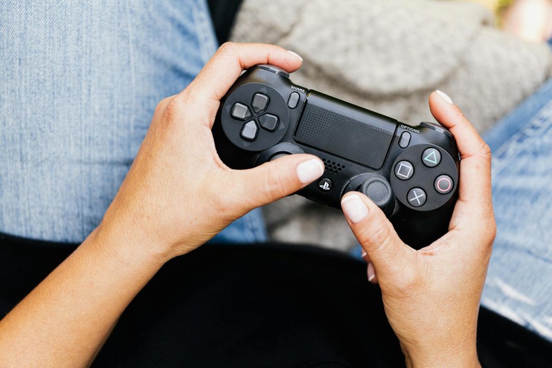 Close-up of hands holding a PlayStation gaming controller in a casual indoor setting