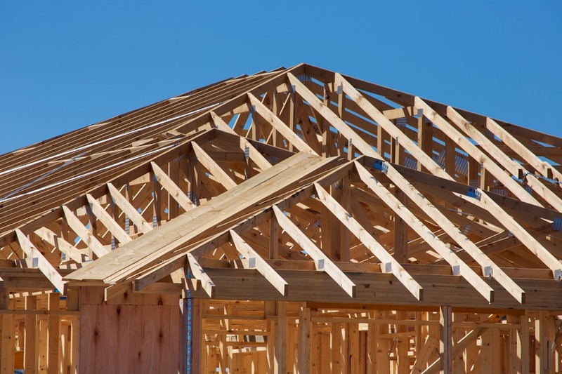 Wooden roof trusses of a house under construction against a blue sky