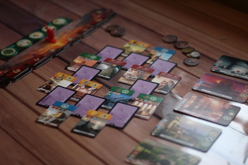 Fantasy-themed card game spread across a wooden table with colorful illustrated cards and tokens