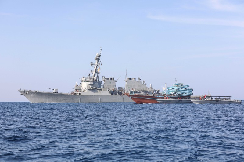 A US Navy guided-missile destroyer operates alongside civilian vessels in the Gulf of Oman.
