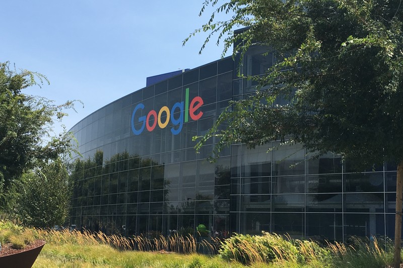 The Googleplex headquarters building in Mountain View, California, with the Google logo prominently displayed on its curved glass facade