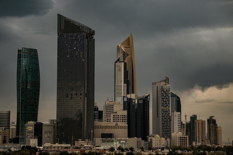 Kuwait City skyline under dark, stormy clouds with modern skyscrapers