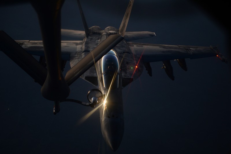 A US military fighter jet refuels from a KC-135 Stratotanker during a nighttime aerial refueling operation