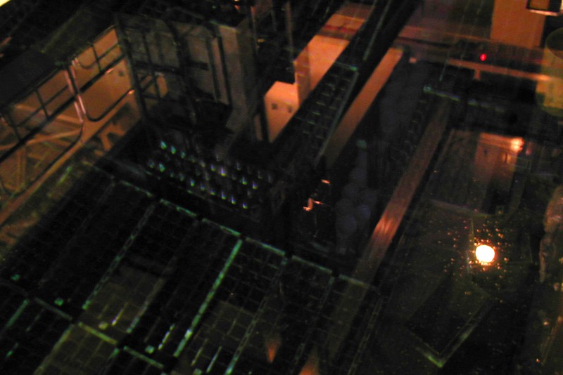 Dimly lit view of the spent fuel pool inside a reactor building at Fukushima Daiichi Nuclear Power Plant, showing water surface and industrial framework