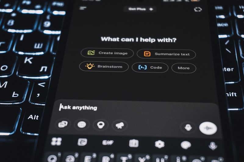 Smartphone displaying an AI assistant interface resting on a backlit keyboard
