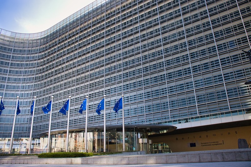 Modern glass building with European Union flags on flagpoles in front